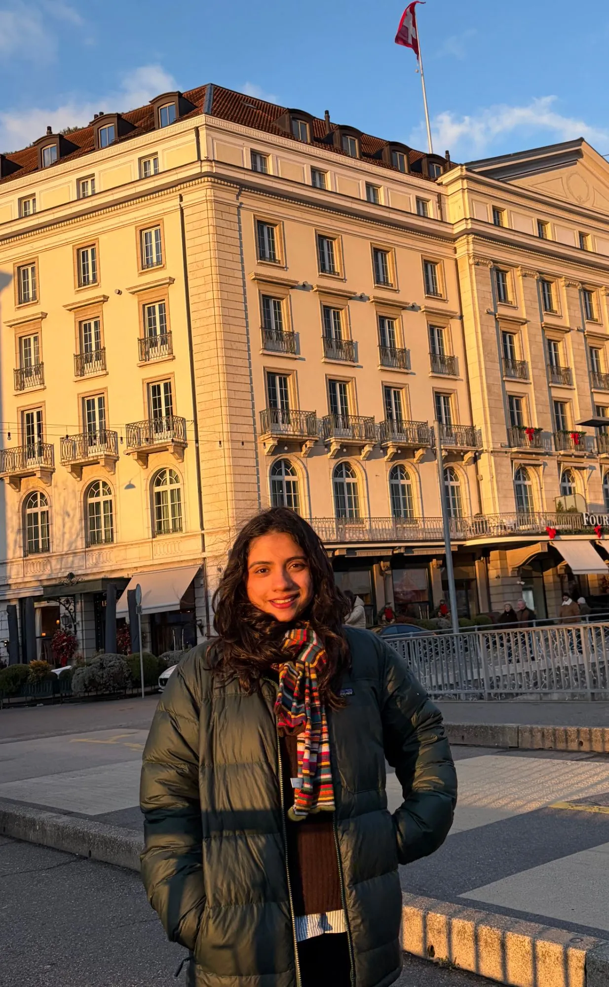 Smiling in golden evening light in front of a grand hotel, Swiss flag on the roof
