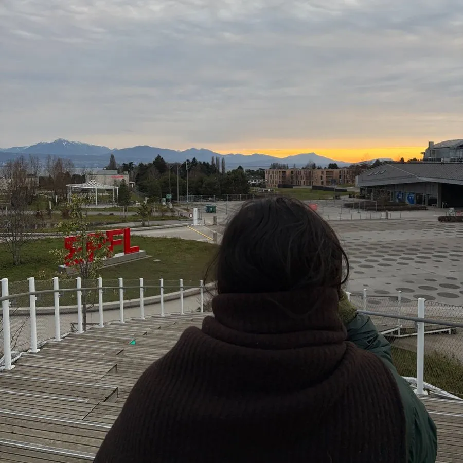 Swastika from behind, looking out over the EPFL campus toward the mountains at sunset